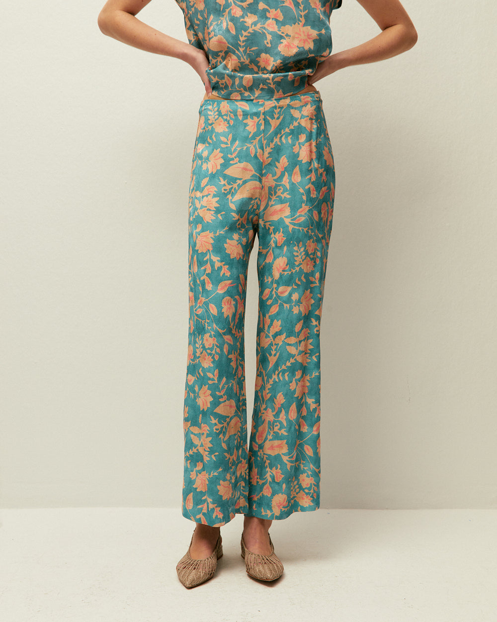 Pantaloni stile capri con pieghe anteriori e stampa floreale.