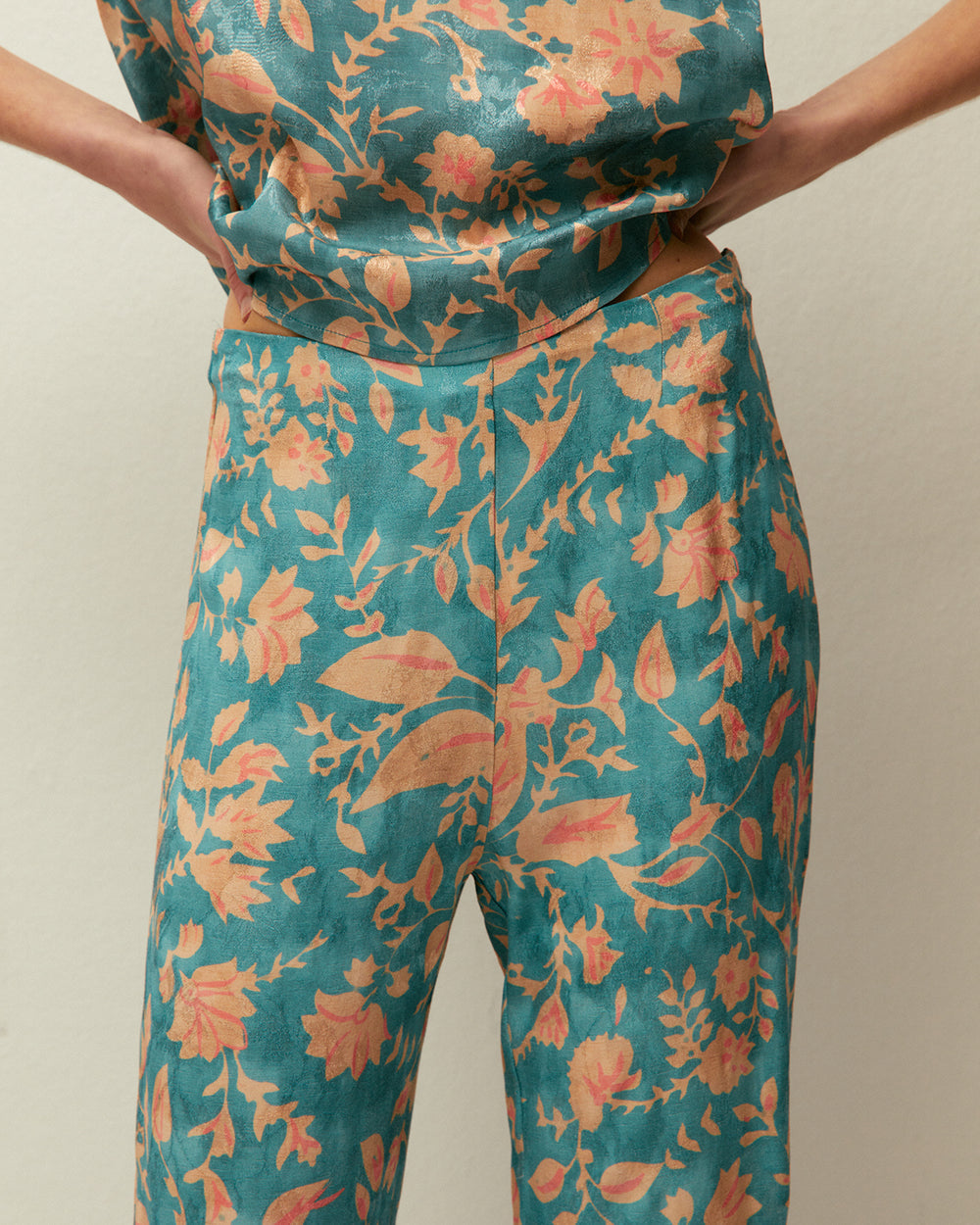 Pantaloni stile capri con pieghe anteriori e stampa floreale.