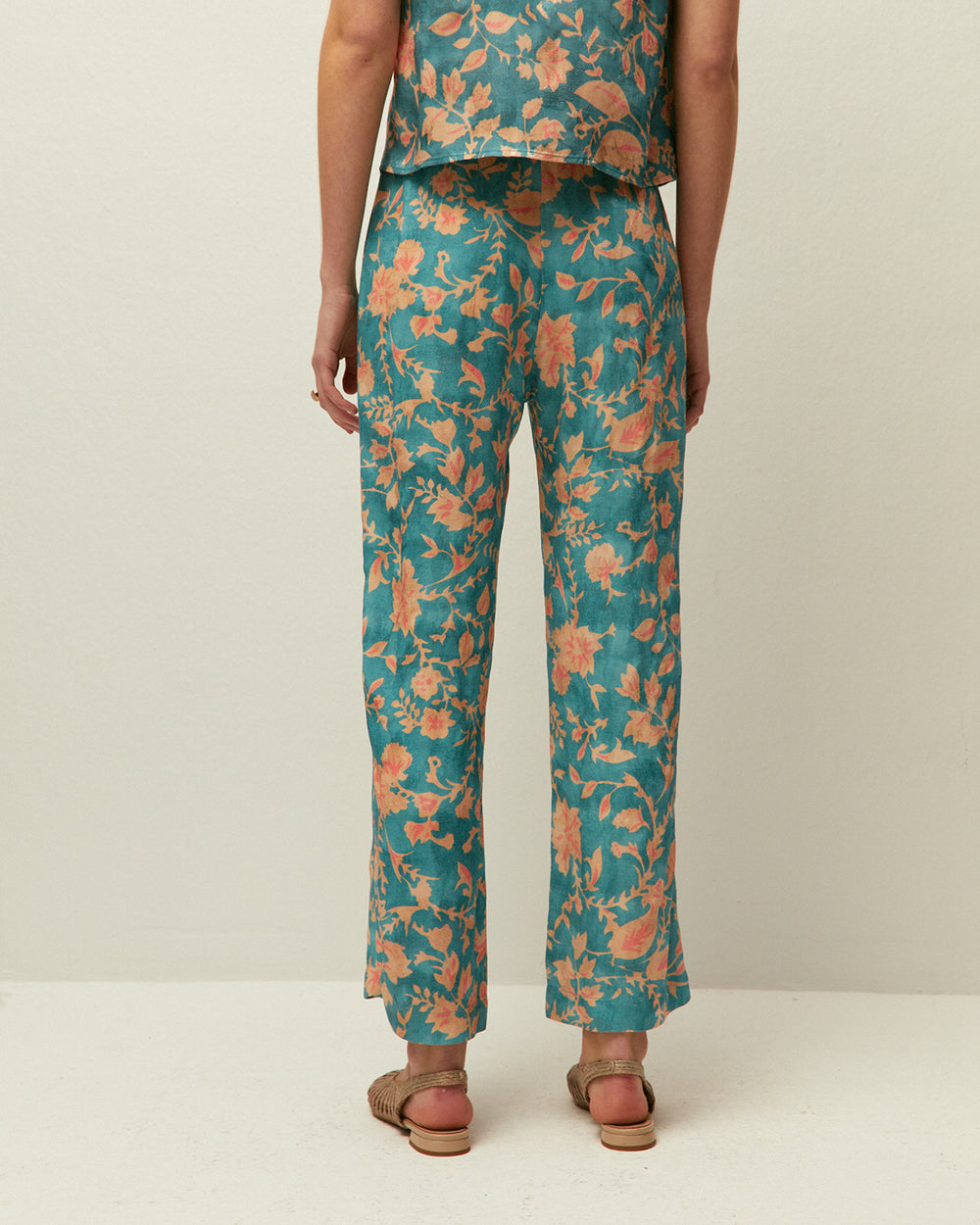 Pantaloni stile capri con pieghe anteriori e stampa floreale.